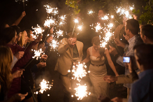 couple exits wedding through glowing sparklers